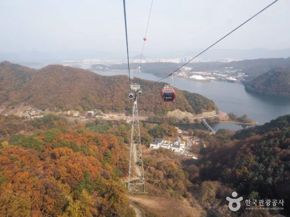 단풍 든 산비탈 위로 케이블이 길게 뻗고 빨간 캐빈이 의암호 쪽으로 내려가는 삼악산 호수케이블카