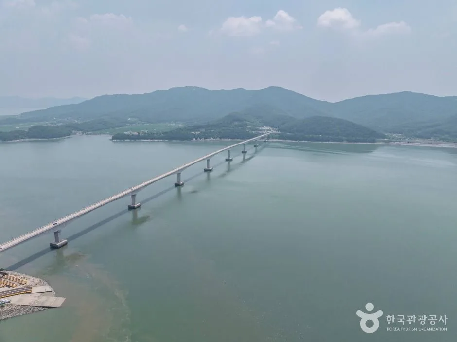 잔잔한 바다 위로 강화도와 석모도를 잇는 석모대교가 길게 뻗고 뒤로 석모도 산줄기가 겹쳐 보이는 모습