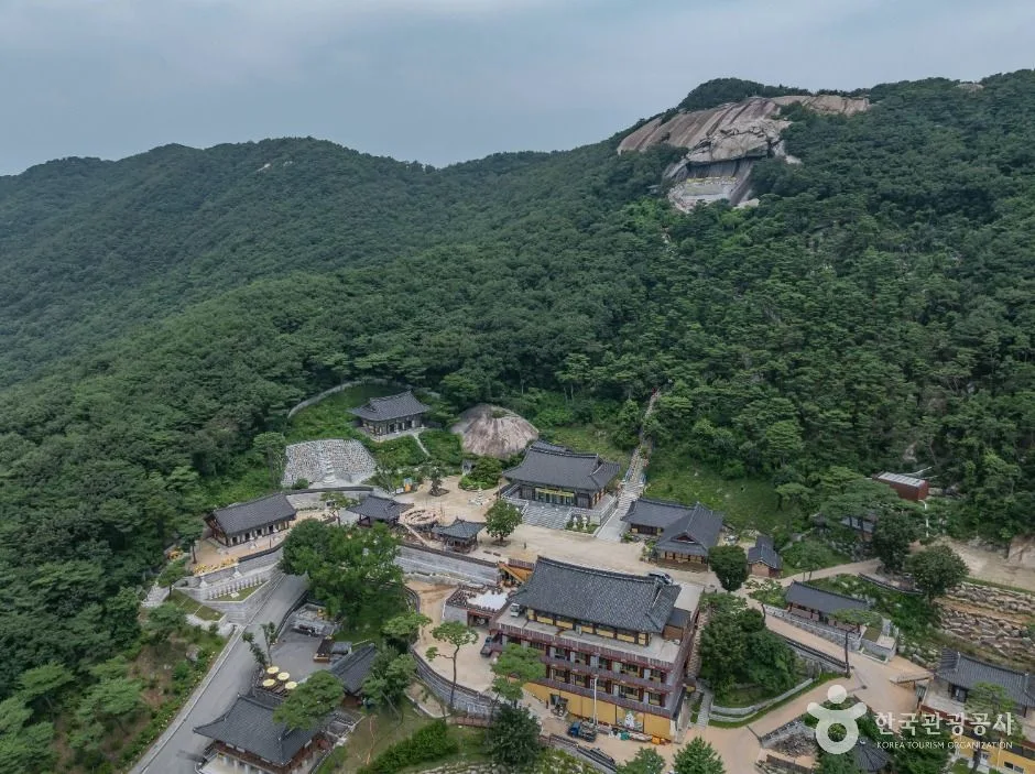 산비탈 숲에 기대 들어선 보문사 전각들과 마당을 위에서 내려다본 모습, 뒤로 바위 봉우리가 보인다