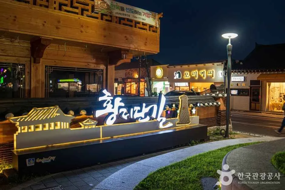 밤 조명이 켜진 한옥 담장 앞에 「황리단길」 글씨 조형물이 빛나는 거리 입구